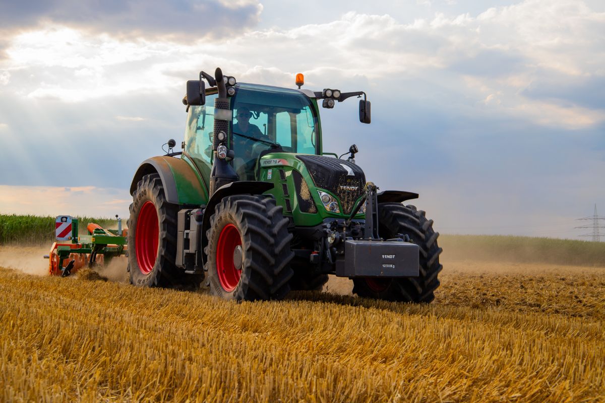Tractor working a field with attached implement at dawn